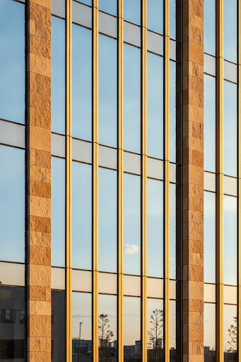 Floor-to-ceiling architectural glazing with slim brass-toned framing against warm stone
